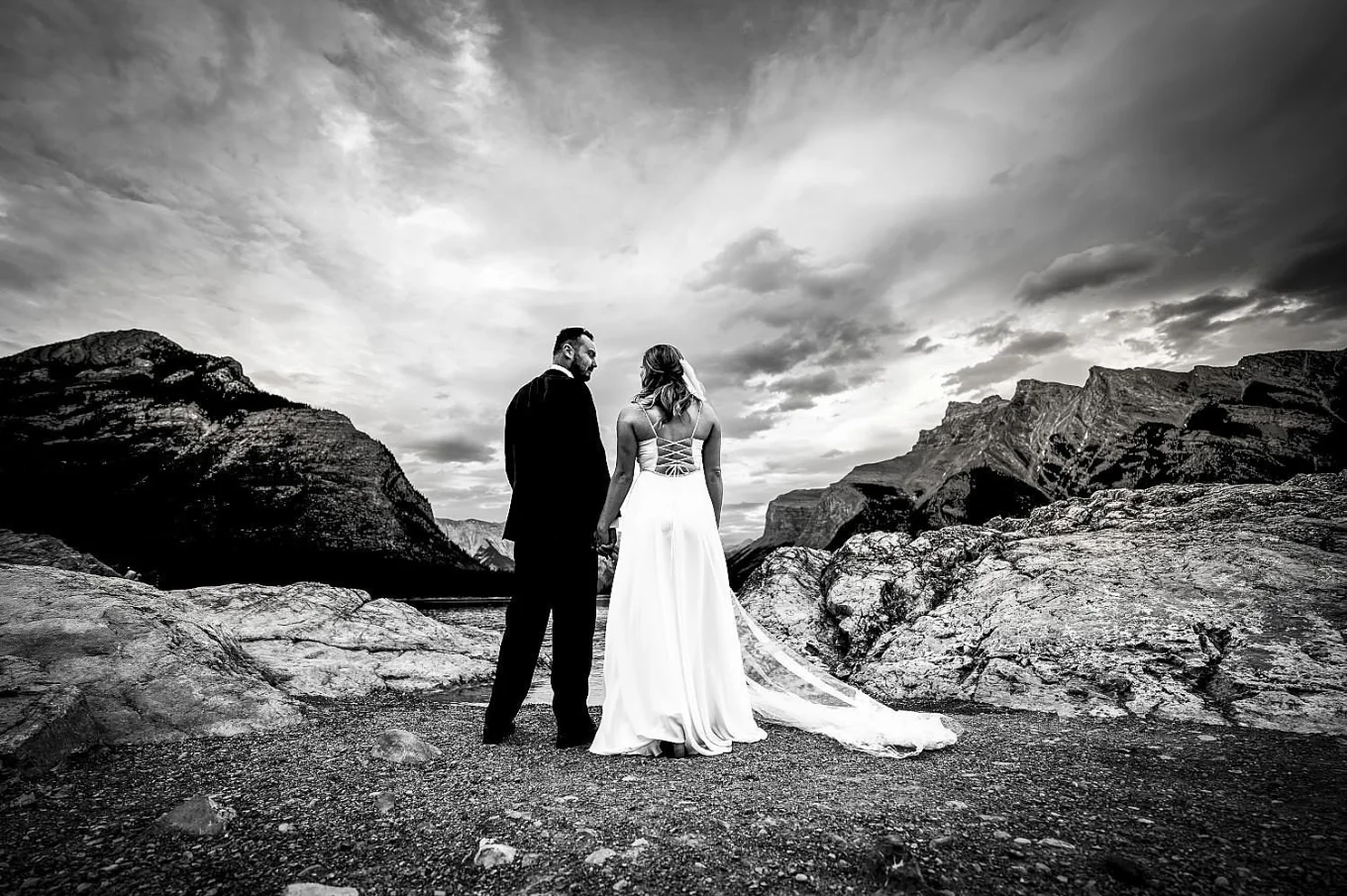 Bride and groom facing Minnewanka Lake and look at each other after Elopeoemt in Banff.