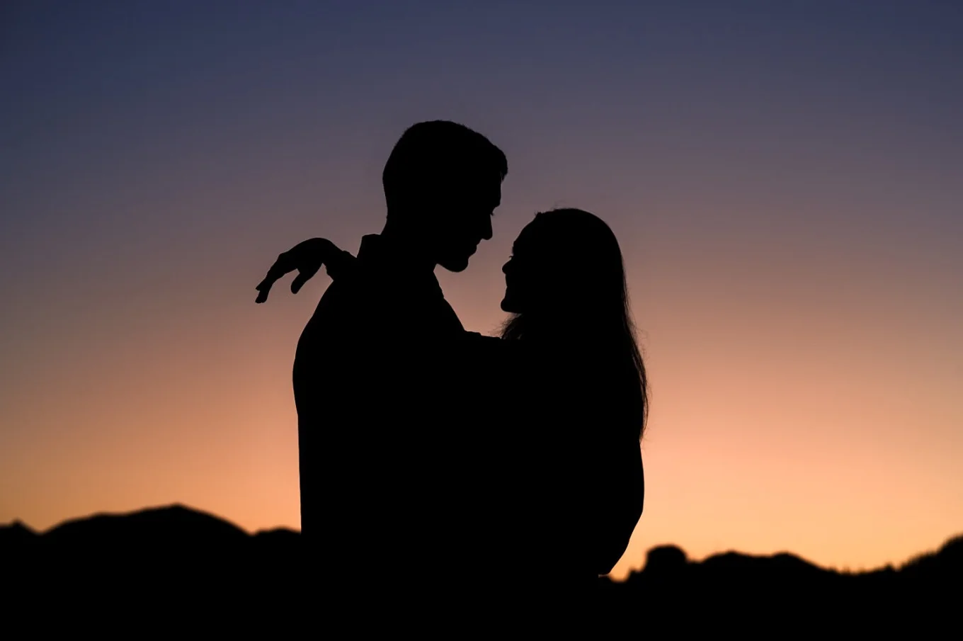 A Canadian, Banff Wedding and Engagement Photographer created creative, situate photograph of engaged couple back-lit by the sunrise at Moraine Lake