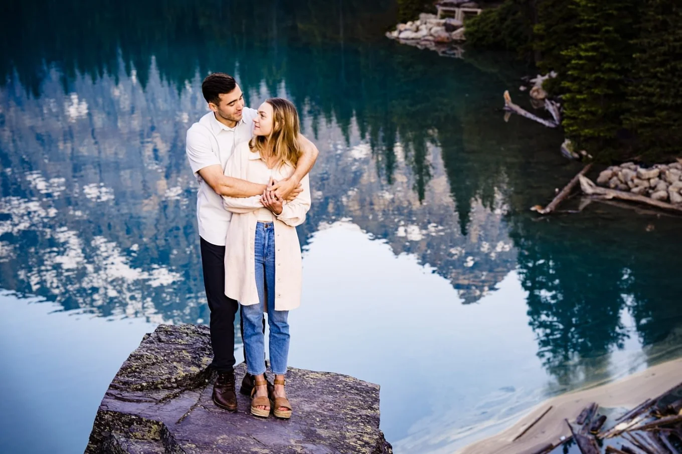 Newly engaged couple poses in front of clear water of Moraine Lake for the best Banff Wedding Photographer 4Eyes Photography.