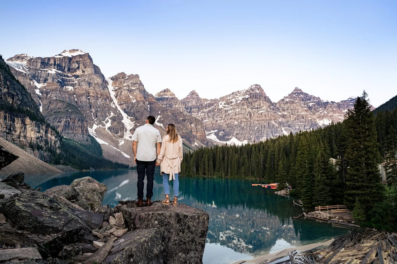 Engaged couple adore the beauty of amazing Moraine Lake in valley of ten peeks