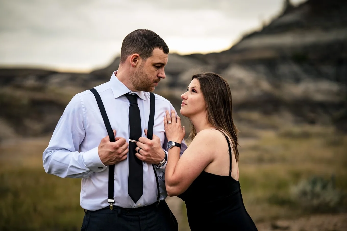 Elegant dressed married couple looking at each other. Lady rest her arm on her husband's shoulder.