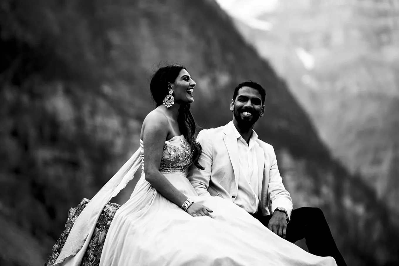 Black and white photography of Indian couple. they sit at the rock and laugh.