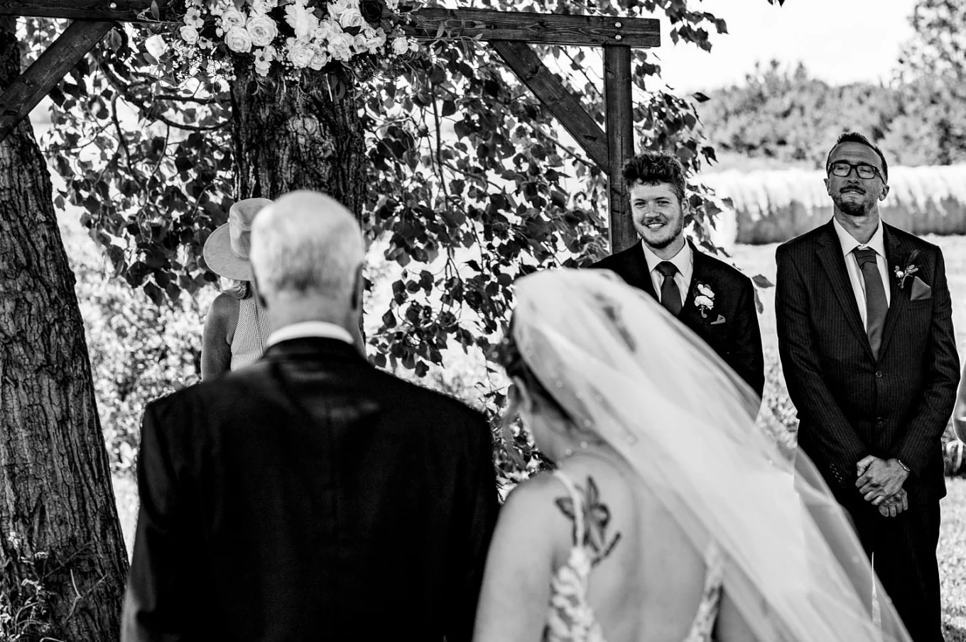 Father walks the bride down the aisle. The groom look at the bride and smiles.