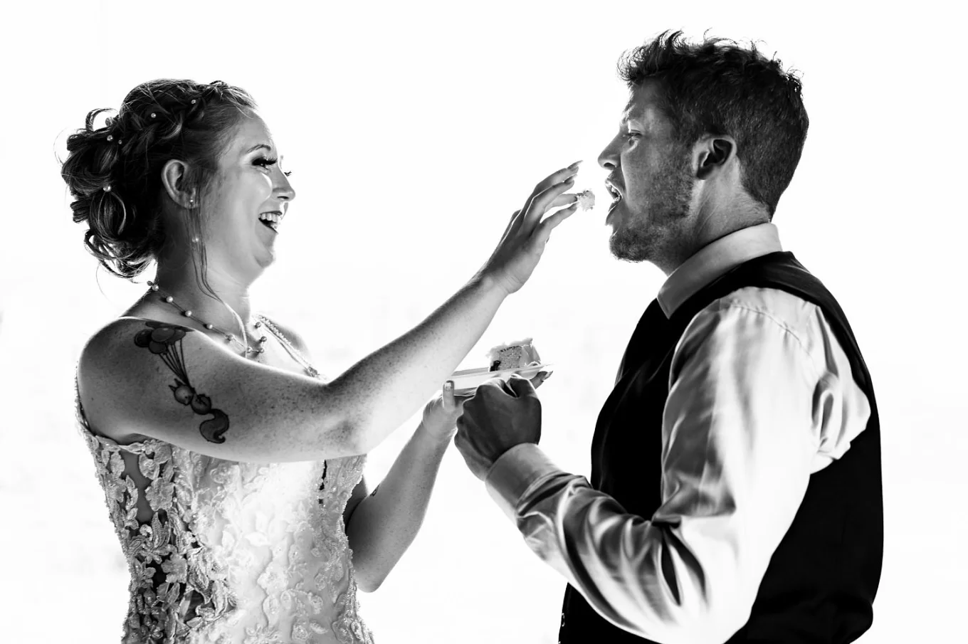 Bride feeds a groom with a piece of wedding cake.