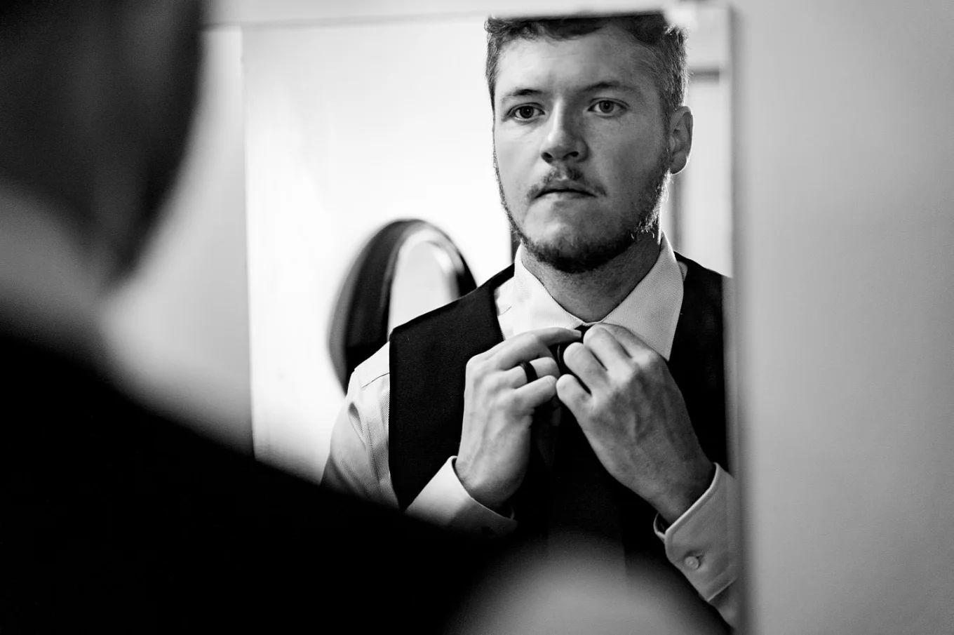 Groom fix his tie and looks at the mirror.