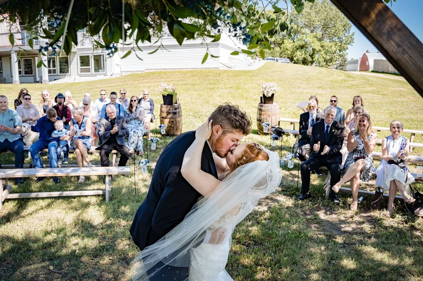 First kiss of the bride and groom. Guest are clapping theirs hands. Studding countryside wedding ceremony outside of Calgary.