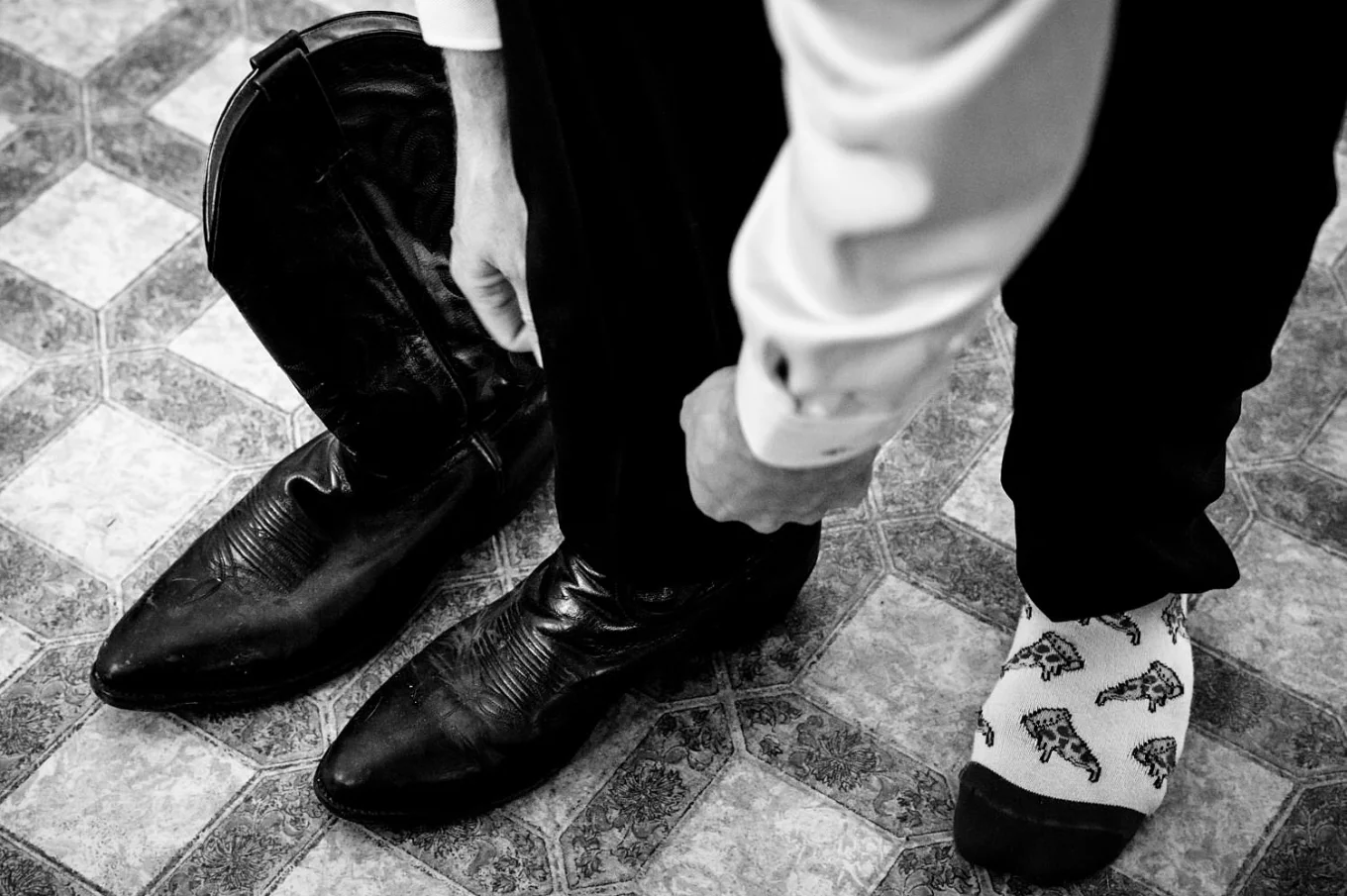 Groom puts a cowboy boots before the countryside wedding ceremony in Calgary.