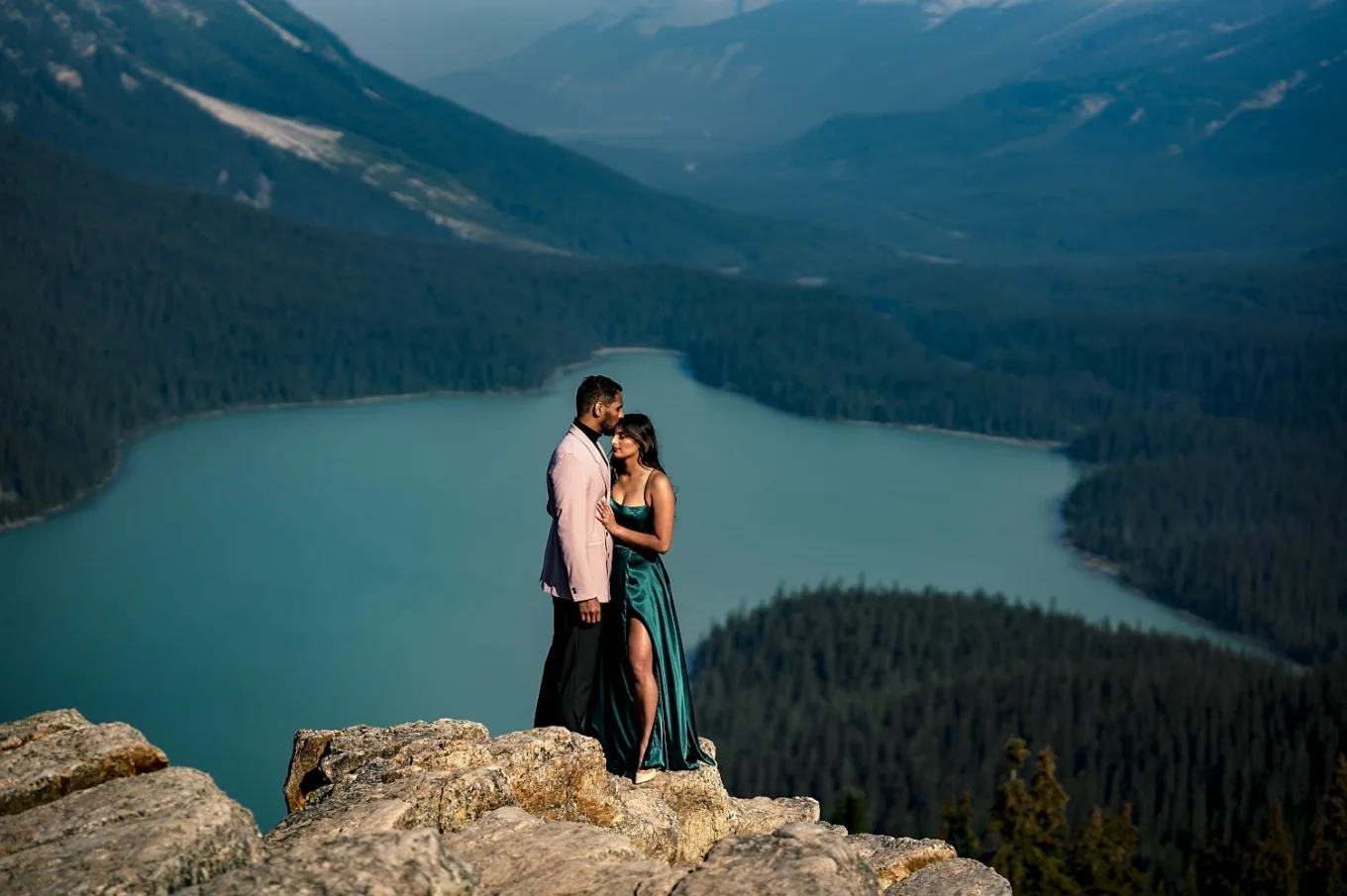 Amazing portrait of engaged couple standing at the top of the mountain. On the background blue Peyto Lake.