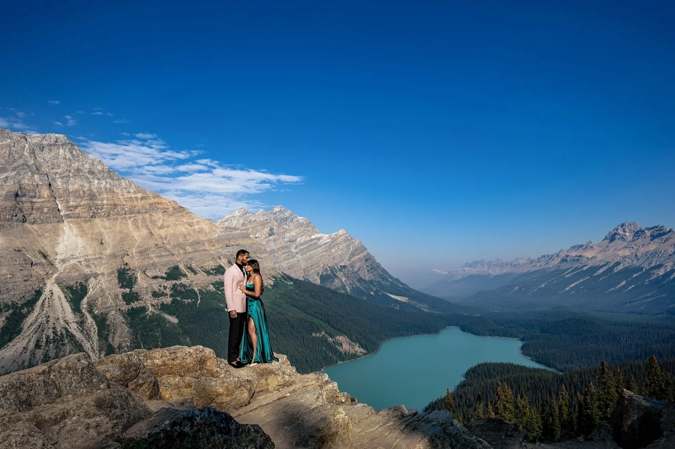 Engaged Photo session at Peyto Lake of couple in love standing at the edge of the mountain in a hug.