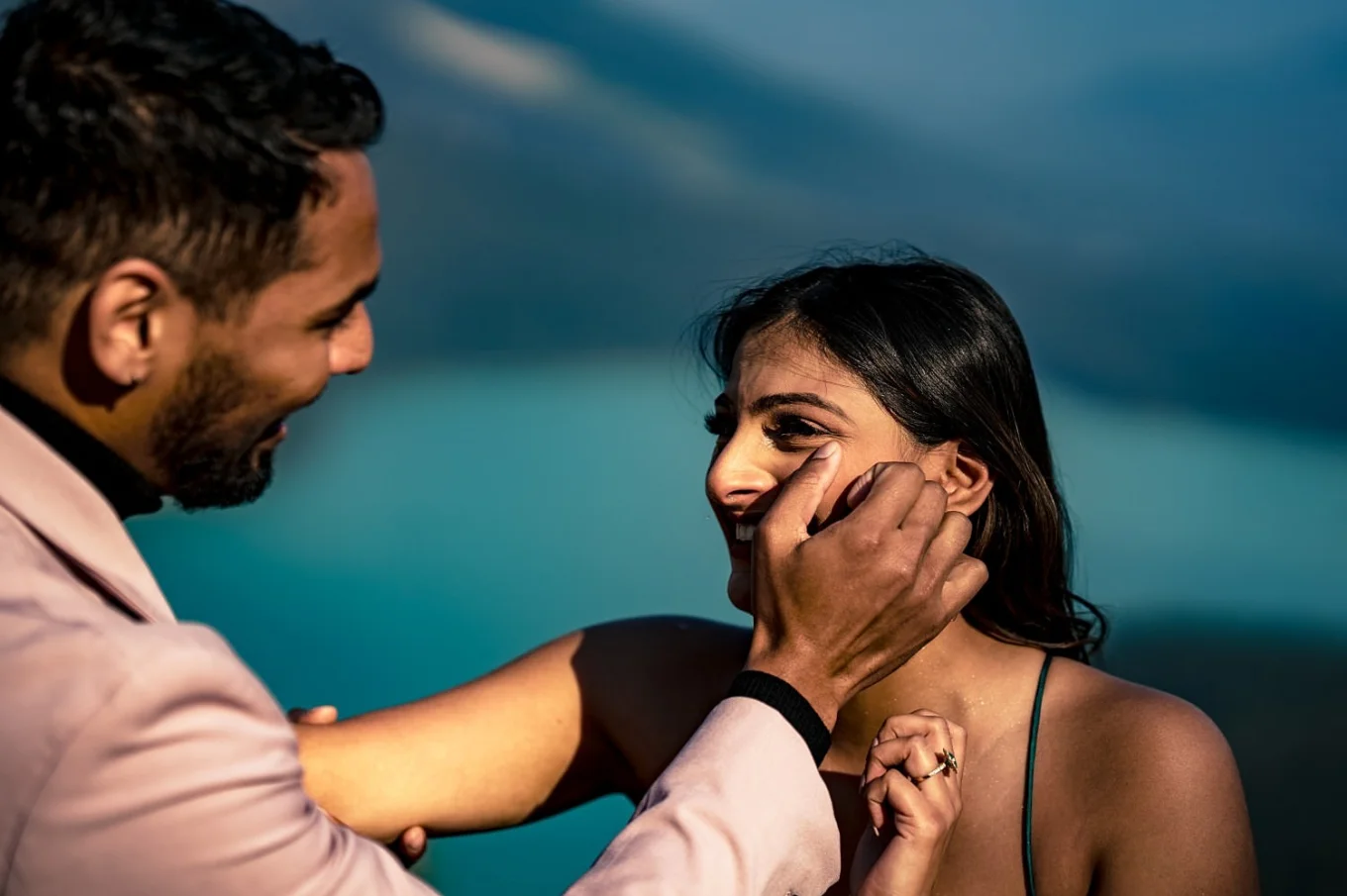 Man wipes the tears of happiness from his fiancee's cheek.