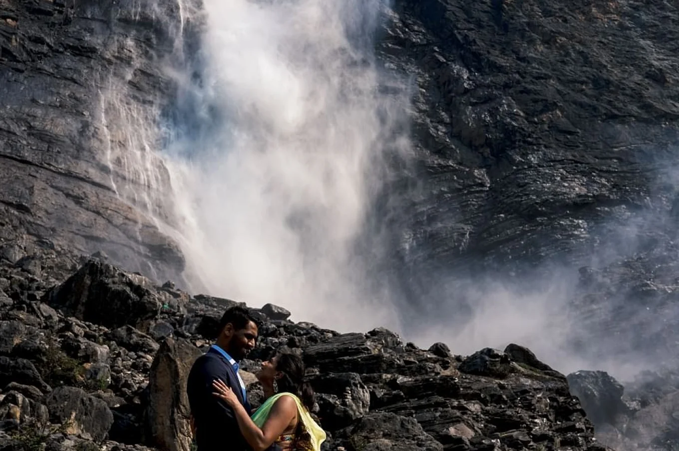 Indian Couple wearing traditional outfits on their engagement session at Takakkaw Falls. They look deeply into each others eyes.