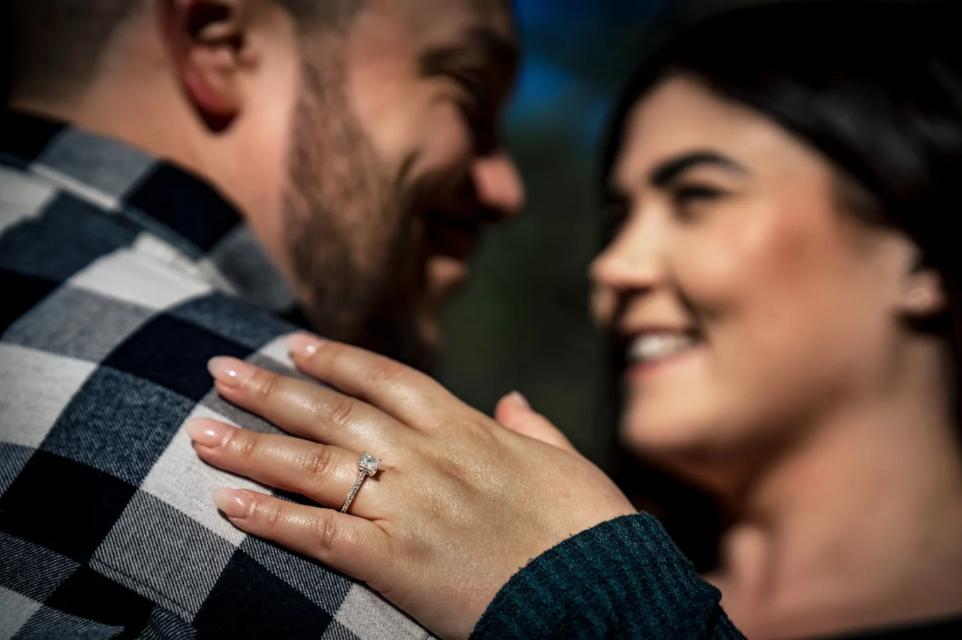 Engaged people look at each other . Girls hand on the man's shoulder with beautiful engagement ring.