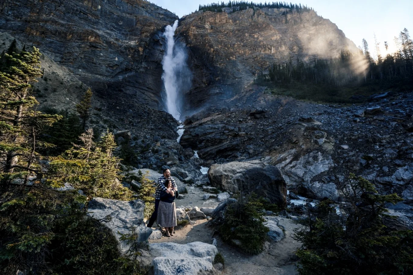 Man hugs his fiancee at amazing waterfall in Banff.