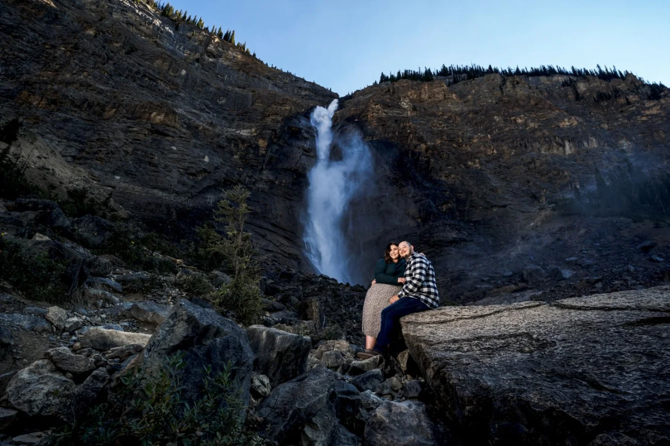 Couple in love sit at the rock at Takakkaw Falls.