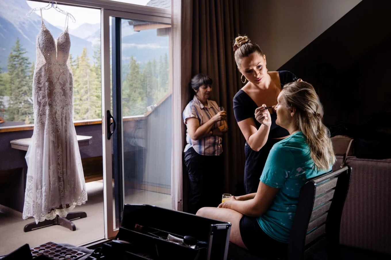 Wedding dress hanging at the window while the bride is getting her make up done.