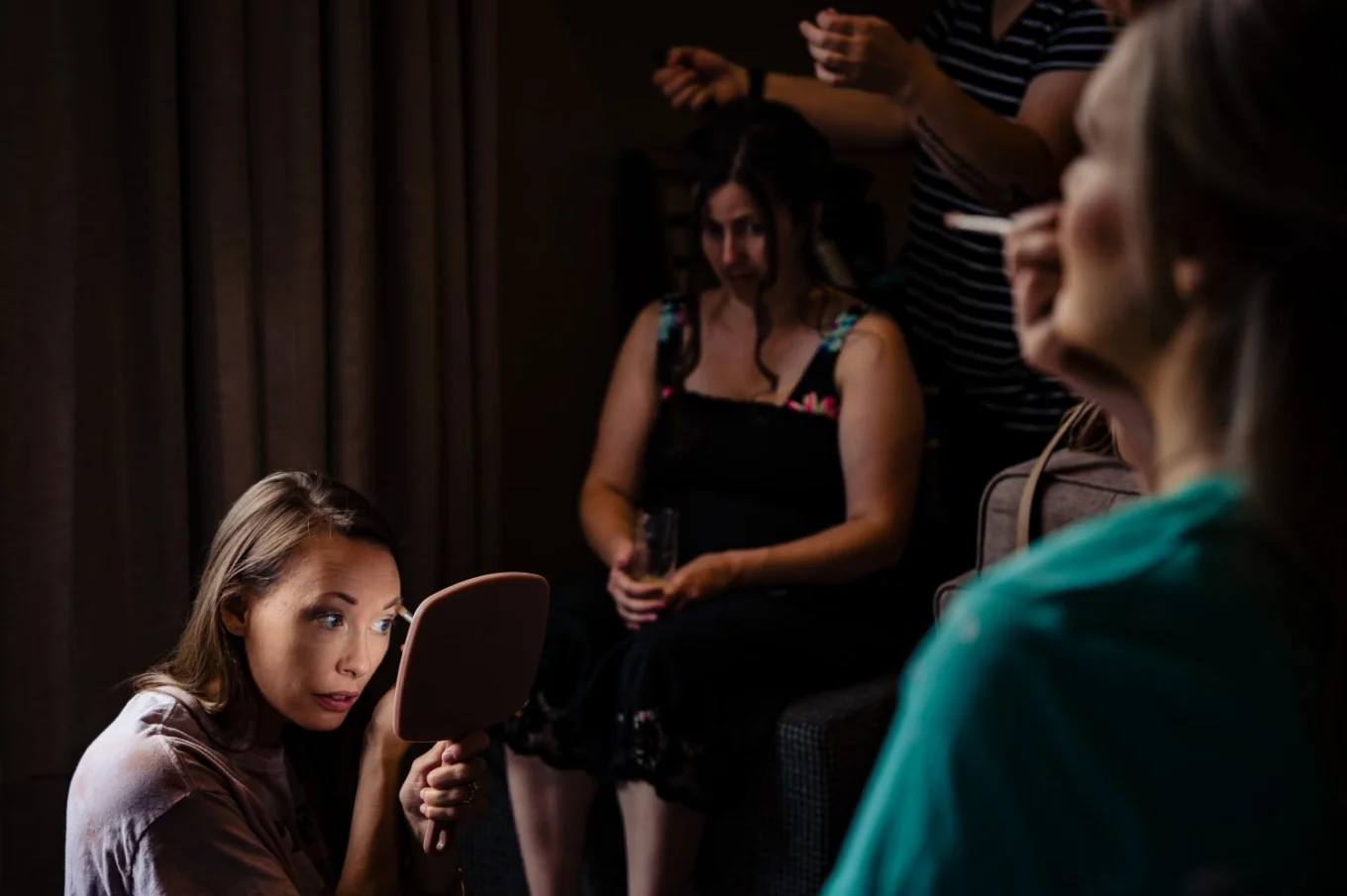 Bridesmaids fix their make up in the hotel room.