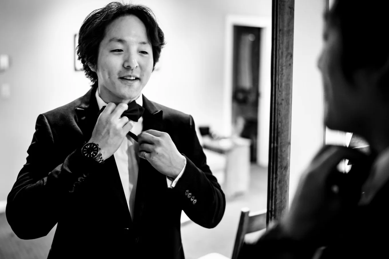 The groom fix his bow tie in front of the mirror before wedding at Emerald Lake.