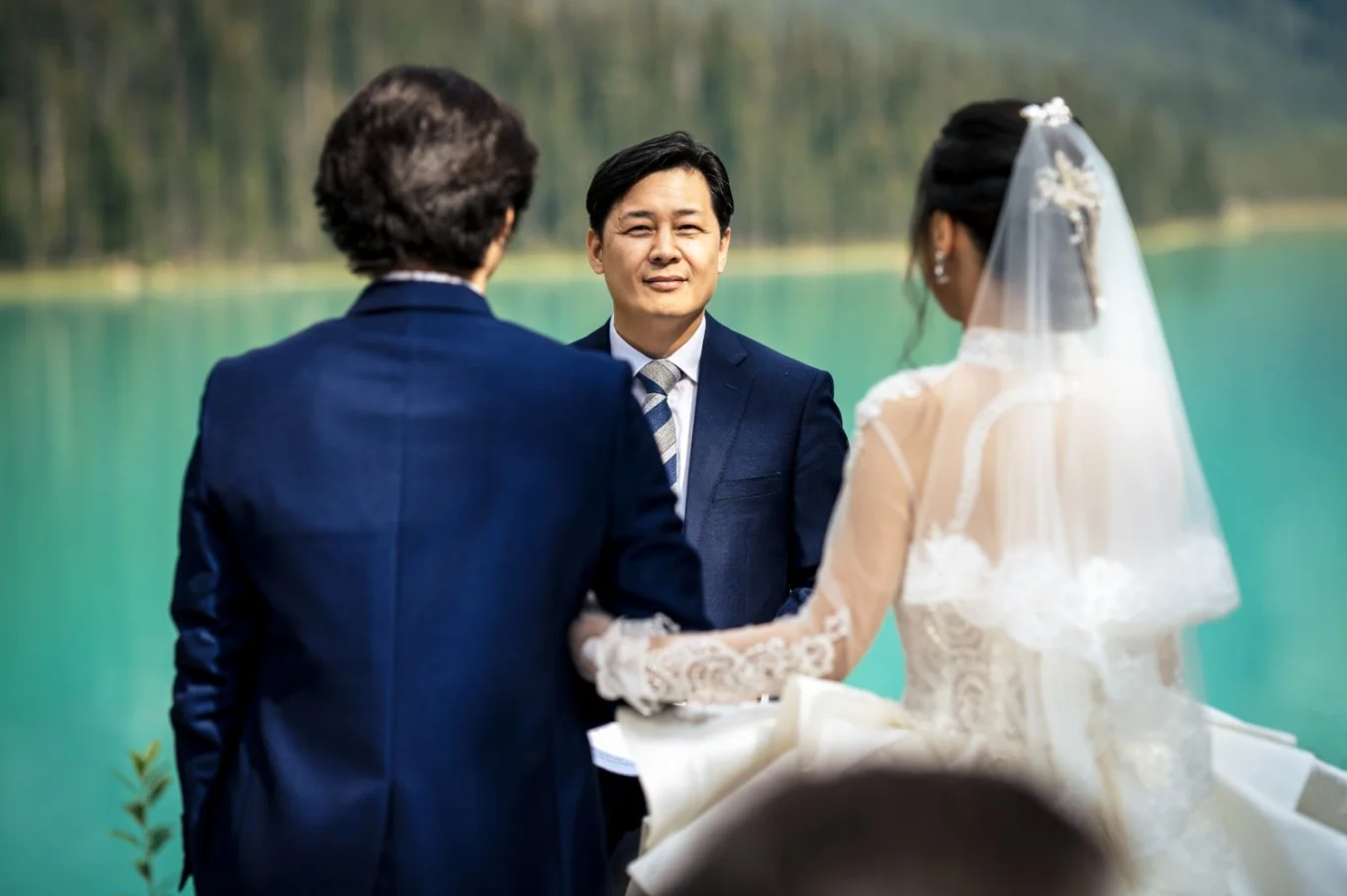 Bride and groom standing in front of officiant At Emerald Lake, Canada