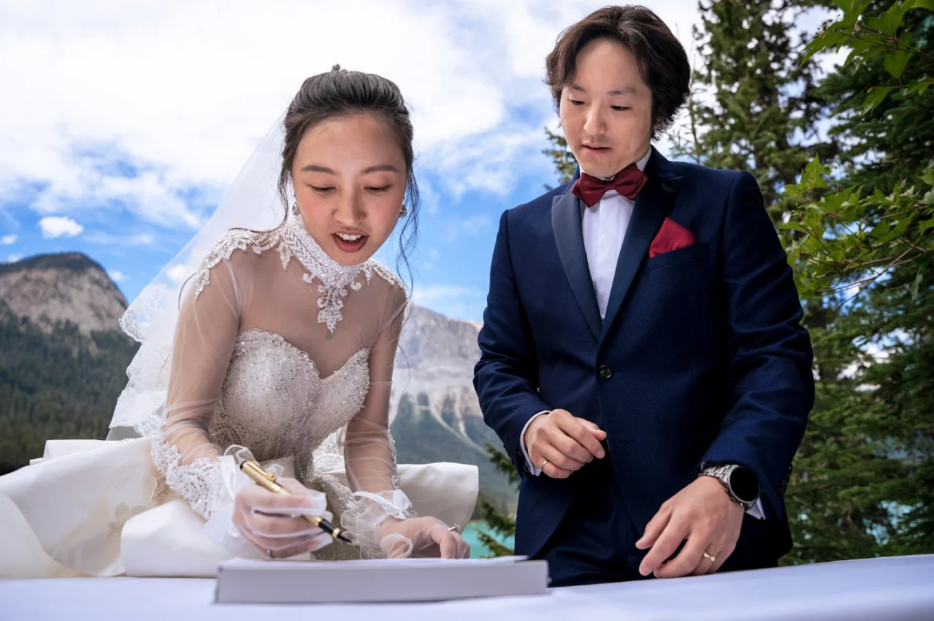 The bride sighs the official papers while the groom watches her.