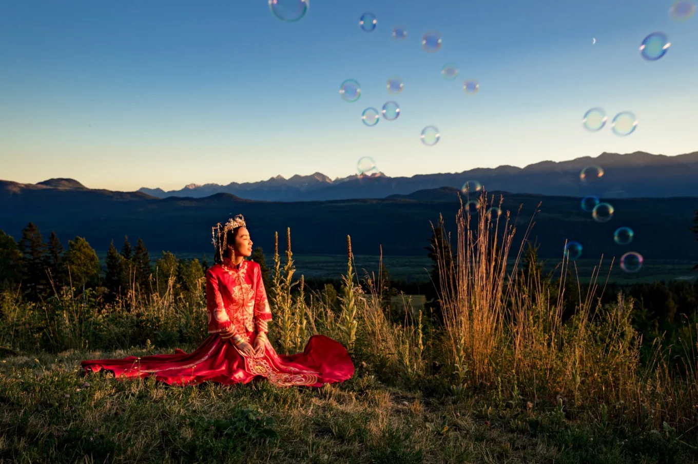 Bride sits on the grass in her stunning , traditional, Asian wedding dress in Bandd.