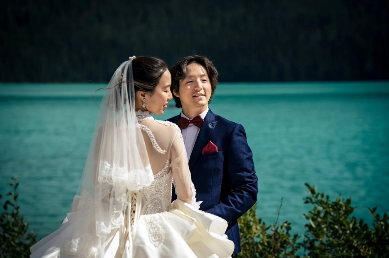 Colourful portrait of bride and groom standing in the sun by the Emerald Lake.
