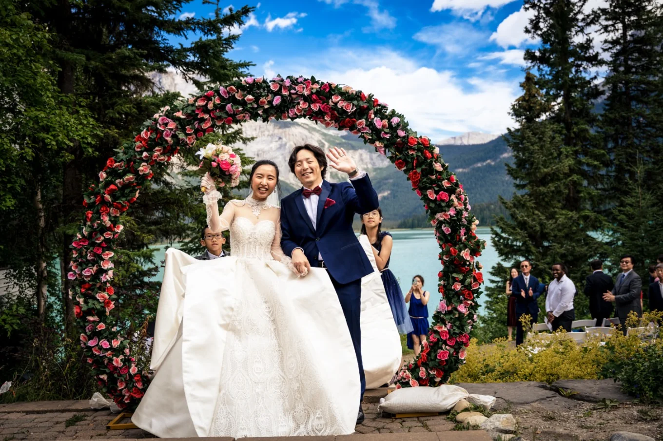 Happy newlyweds after amazing wedding ceremony at Emerald Lake. They smile and the bride lifts her flowers.