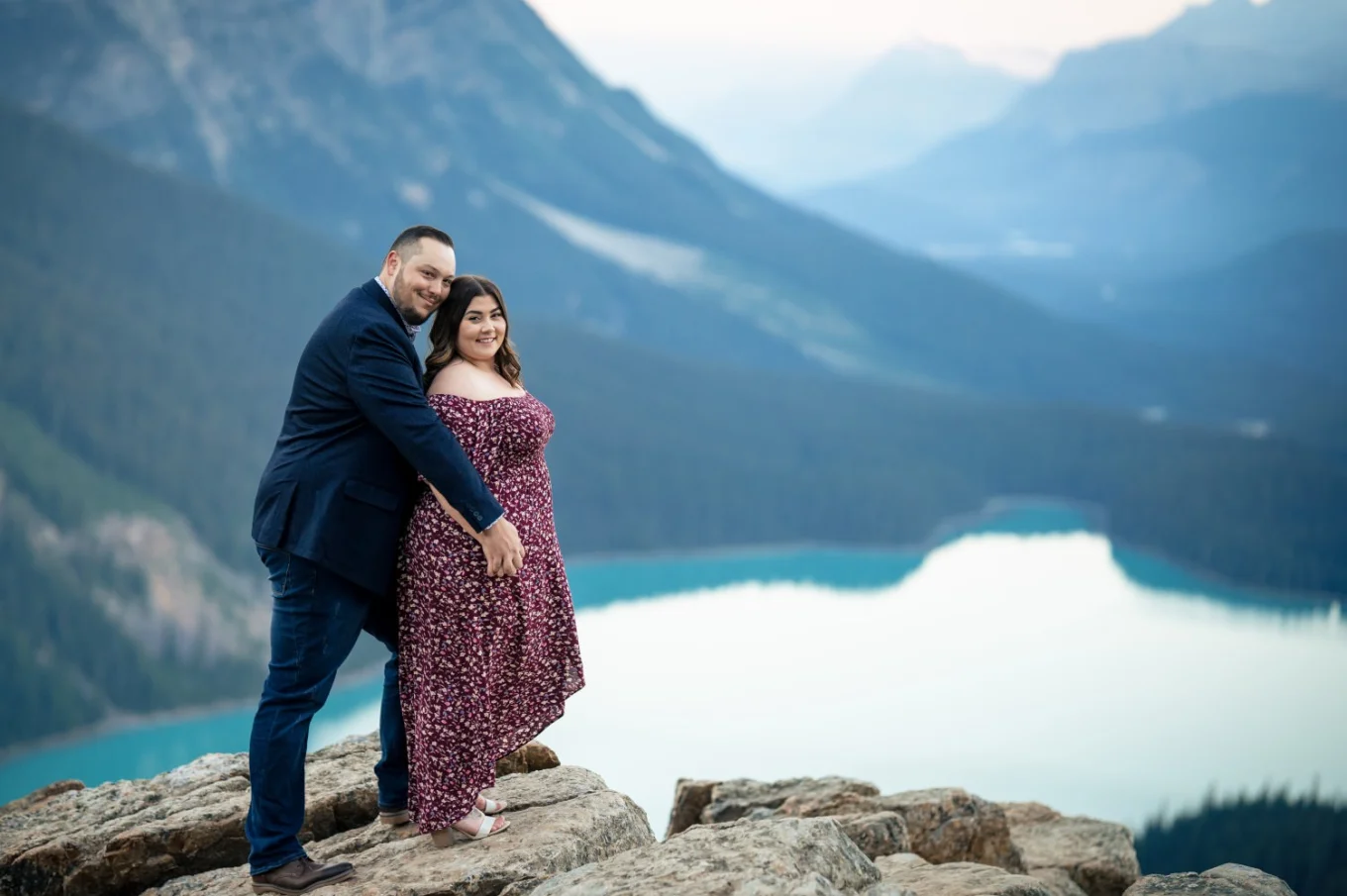 man hugs is fiancee from behind at turquoise Peyto Lake in Banff National Park.