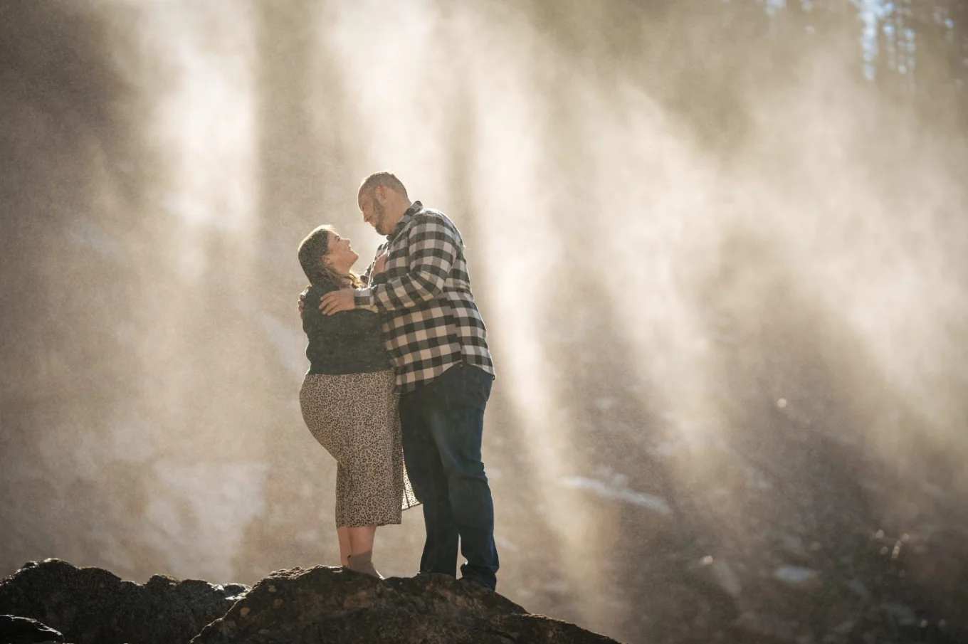 Engaged couple in a hug at amazing Takakkaw Falls in Canada.