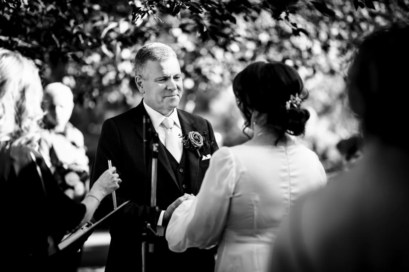 Groom holds the bride's hand during their wedding ceremony in Calgary ZOO
