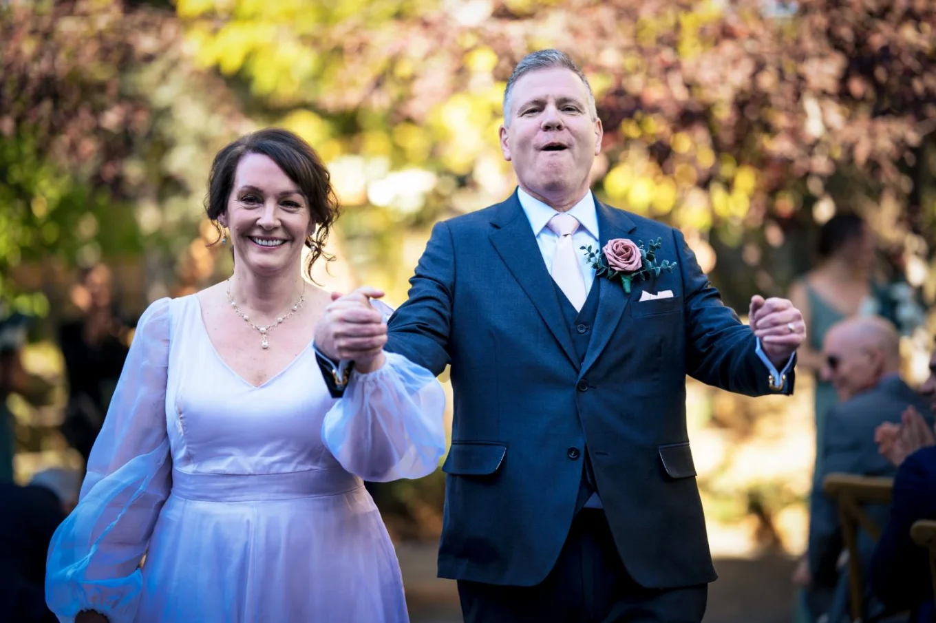 Happy Newlyweds leaving wedding ceremony in Calgary ZOO, holding their hands and smiling.
