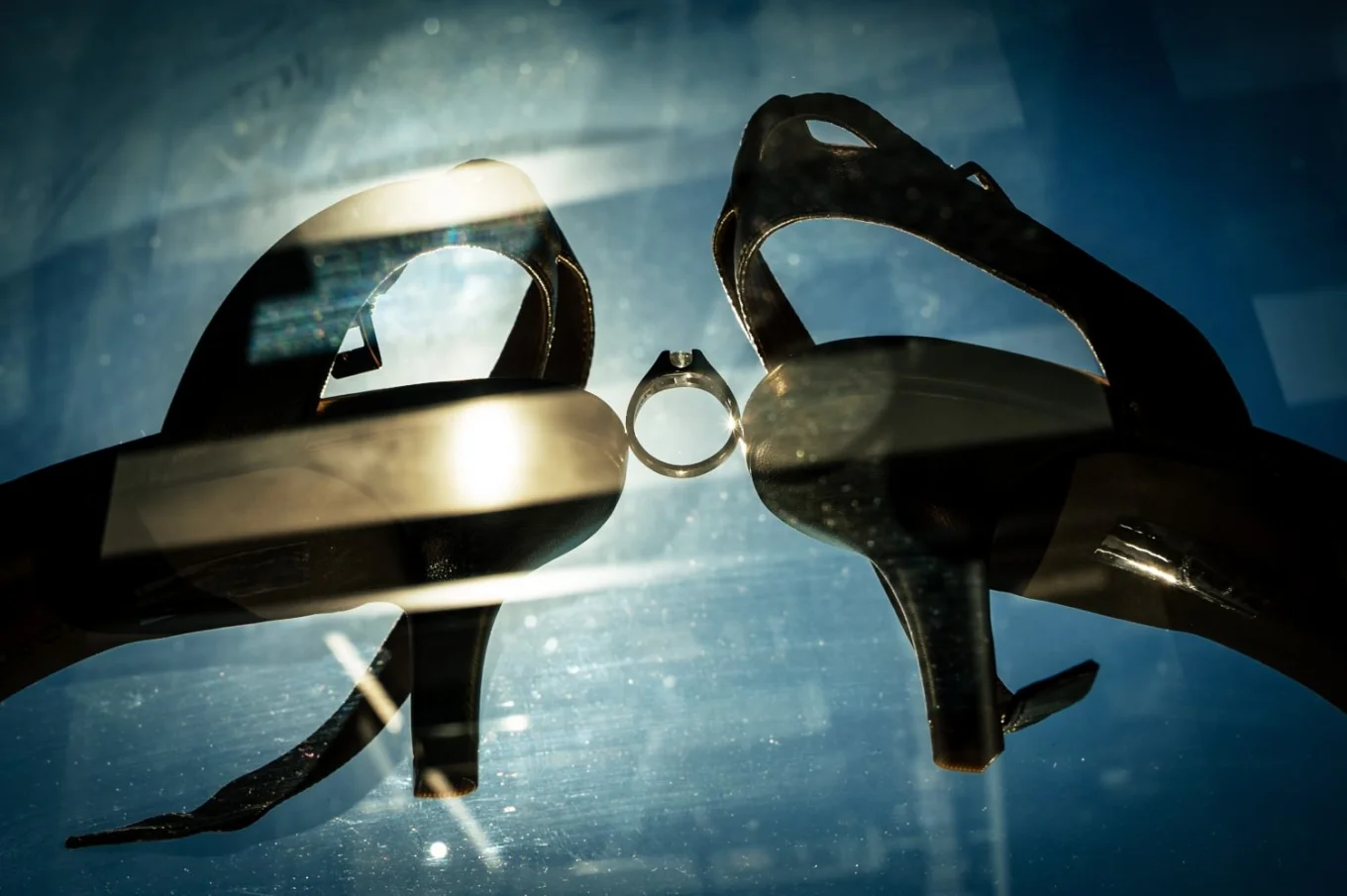 Wedding ring between bride's wedding shoes.