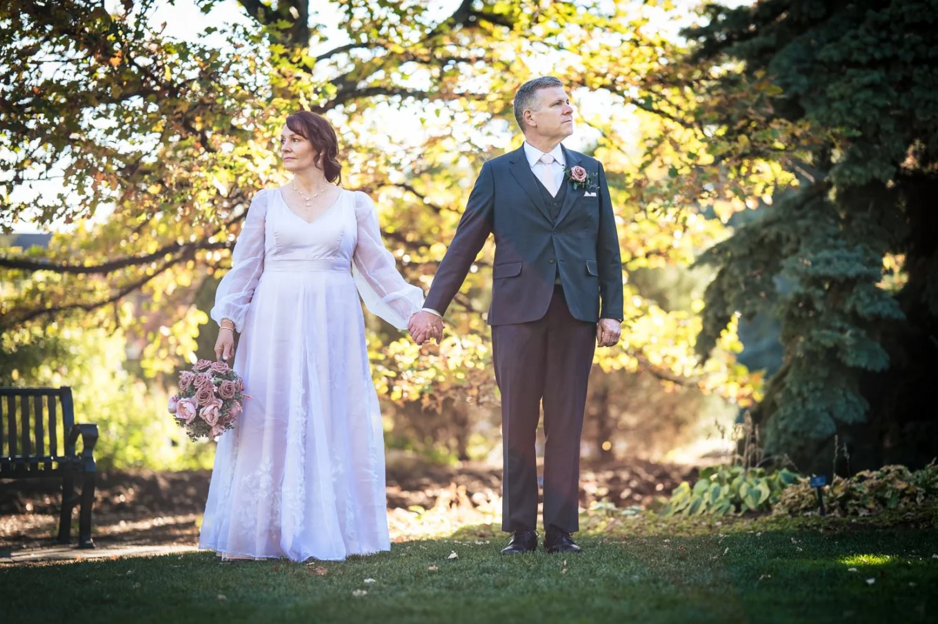 Bride and groom holds their hands while looking in different directions. Calgary Zoo Wedding.
