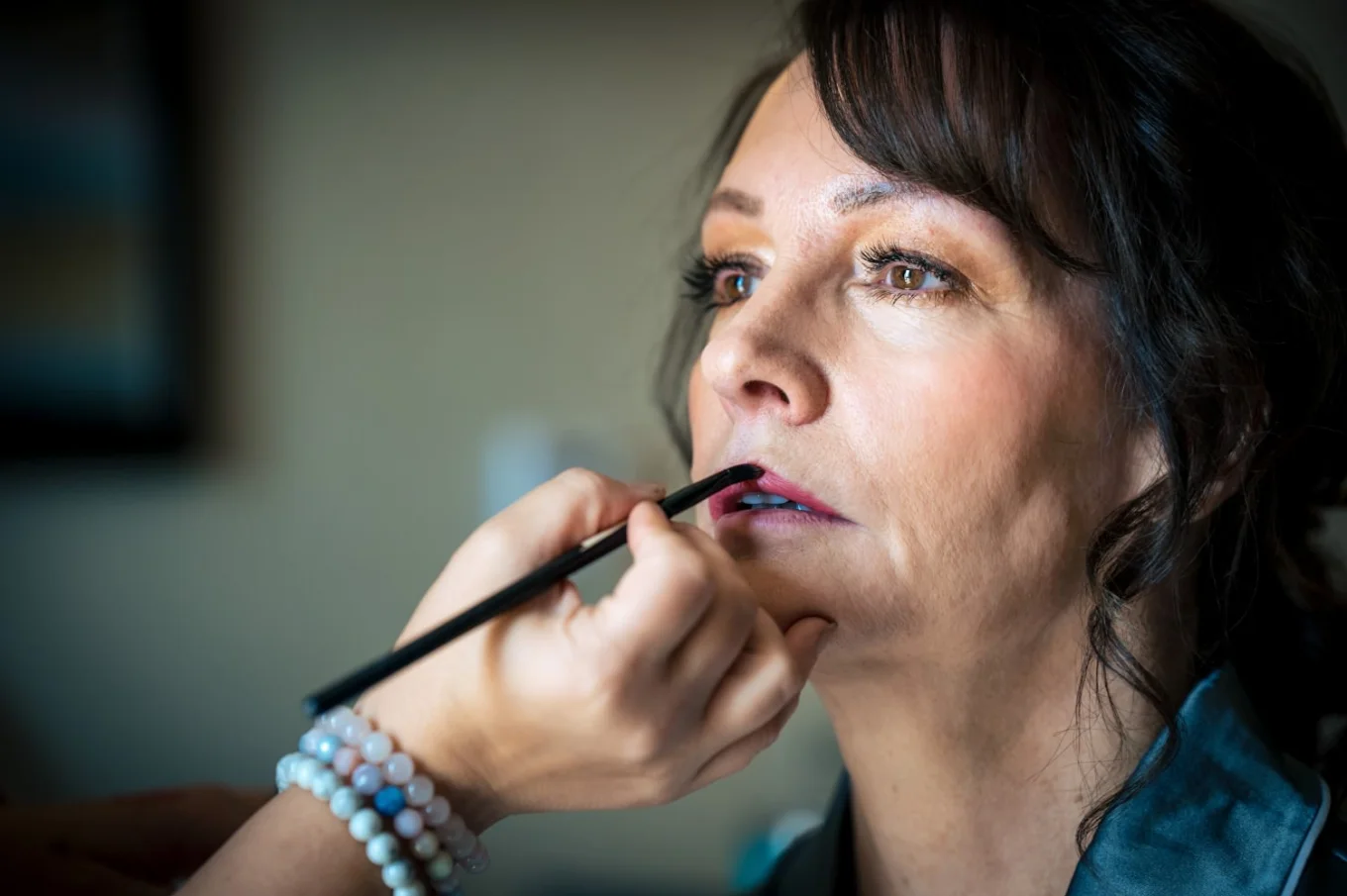 Make up artist puts on the bride's lips a lipstick.