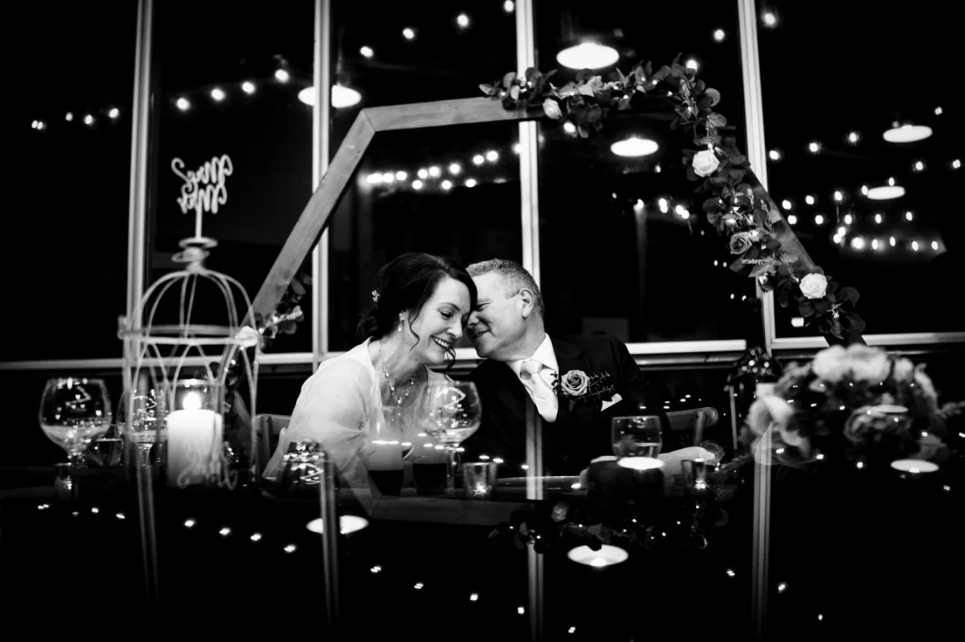 Groom share a secret with his wife during the reception. Photography in black and white with amazong reflaction.