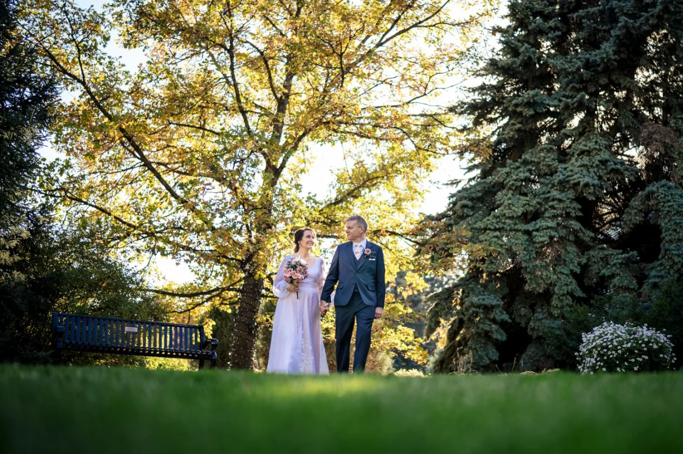 Handsome newlyweds walking holding their hands in Calgary Zoo during the fall.
