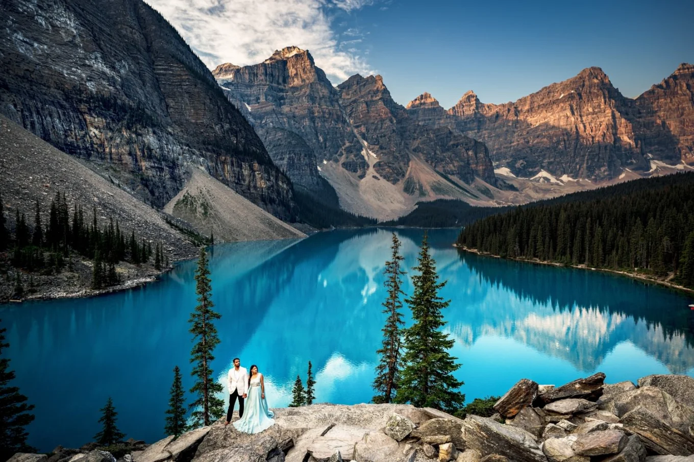 Banff Wedding Photography by Moraine Lake. Couple in love stand at edge of turquoise Lake with the view on huge Rocky Mountains.