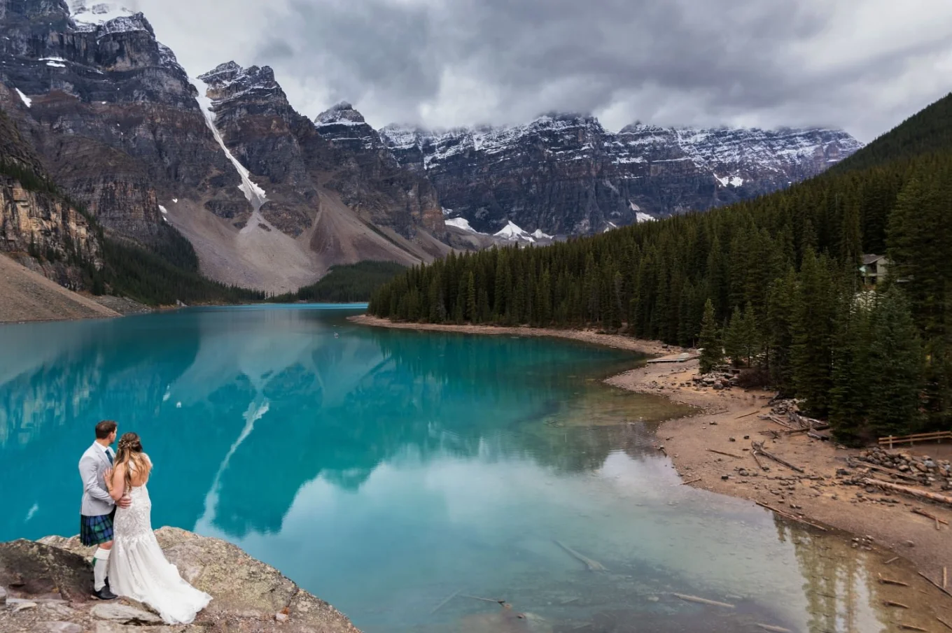 Bride and groom look and the fascinating , turquoise Glacier lake - Moraine Lake.