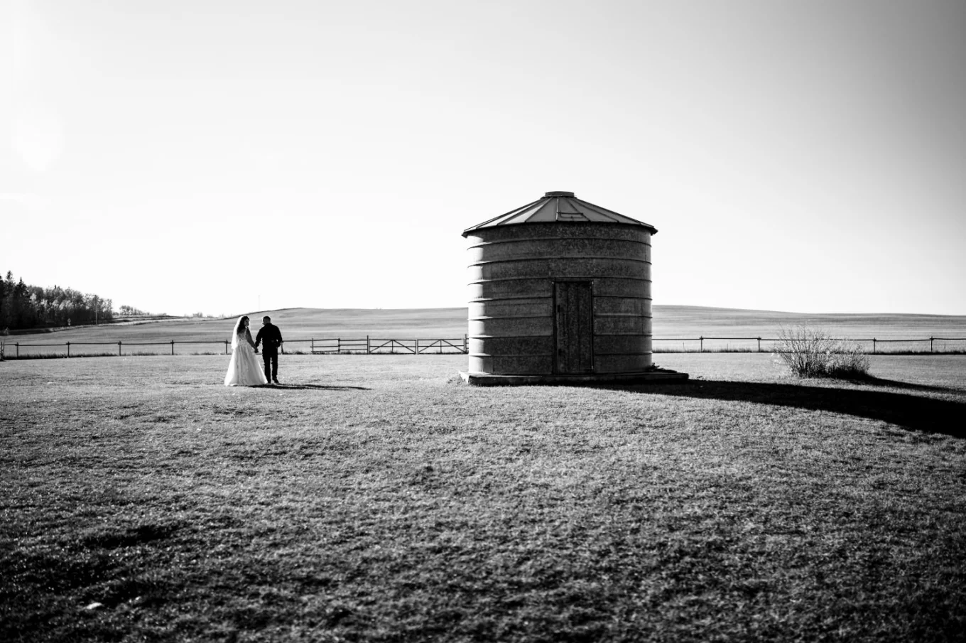 Amazing black and white Calgary Wedding Photography. Newlyweds walk in the huge filed.
