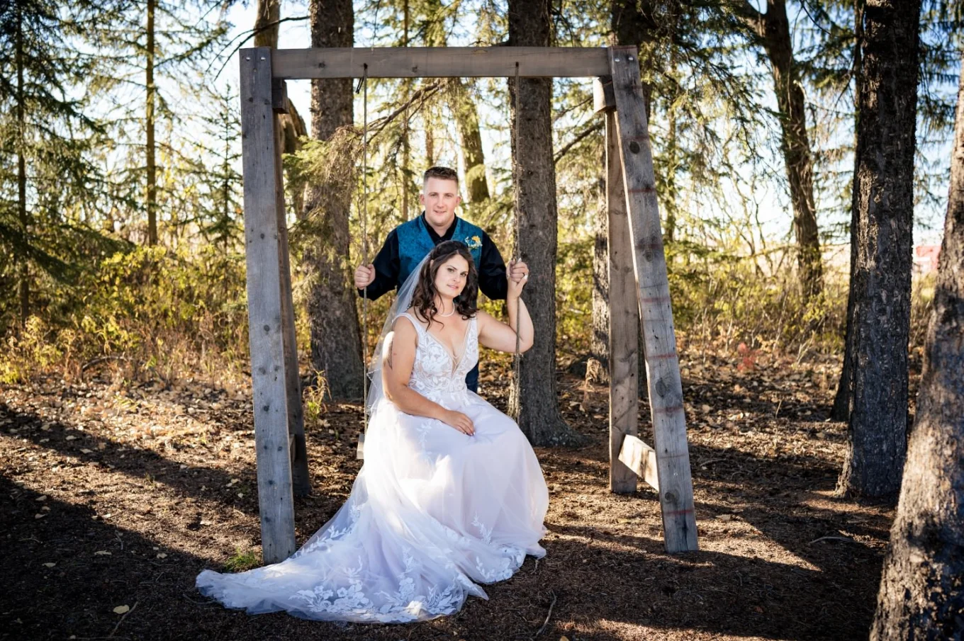 Fall Calgary Wedding Photography of the bride sitting at the swing and the groom standing behind her.