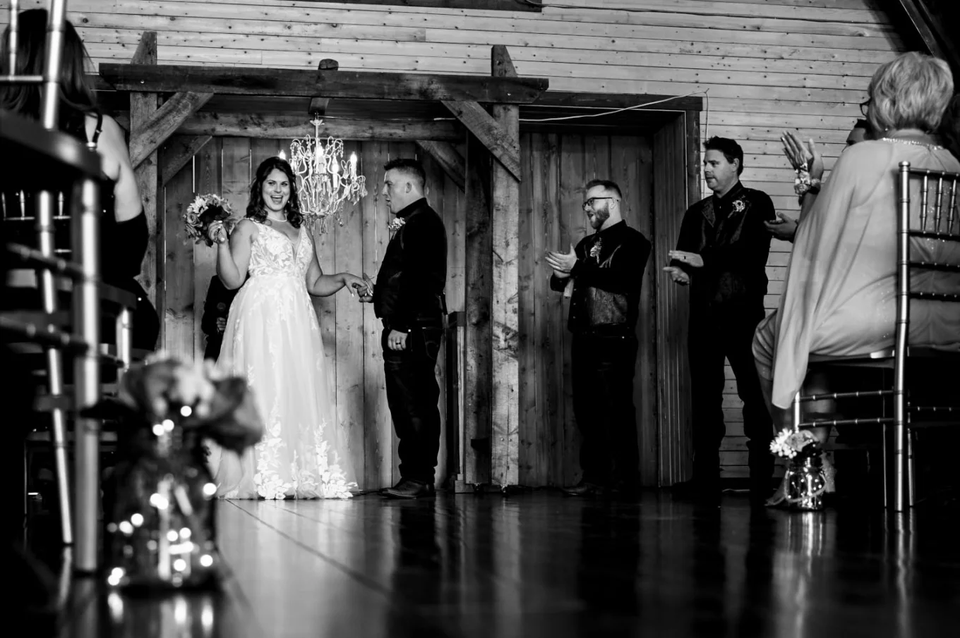 After the Calgary Wedding Ceremony. Bride lifts her bouquet expressing her happiness. Broom look at her.