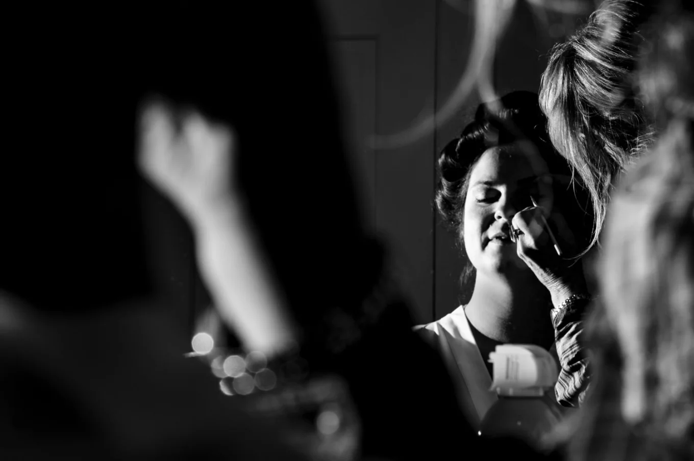 Creative photo in black and white of the bride having her make up done .