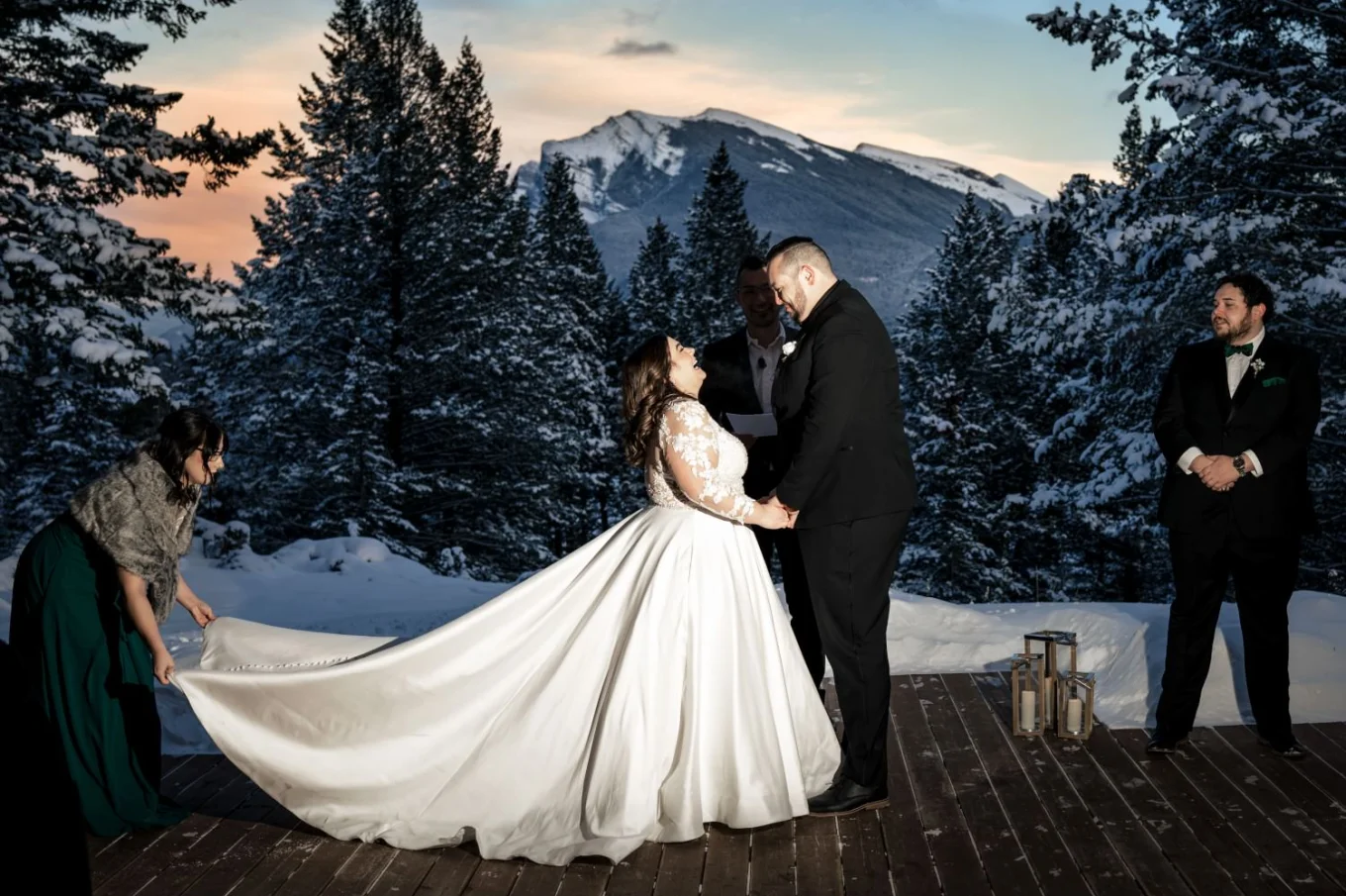 Amazing Banff Wedding Ceremony during winter time and sunset. Bride an groom hold their hands and look into each-others eyes.