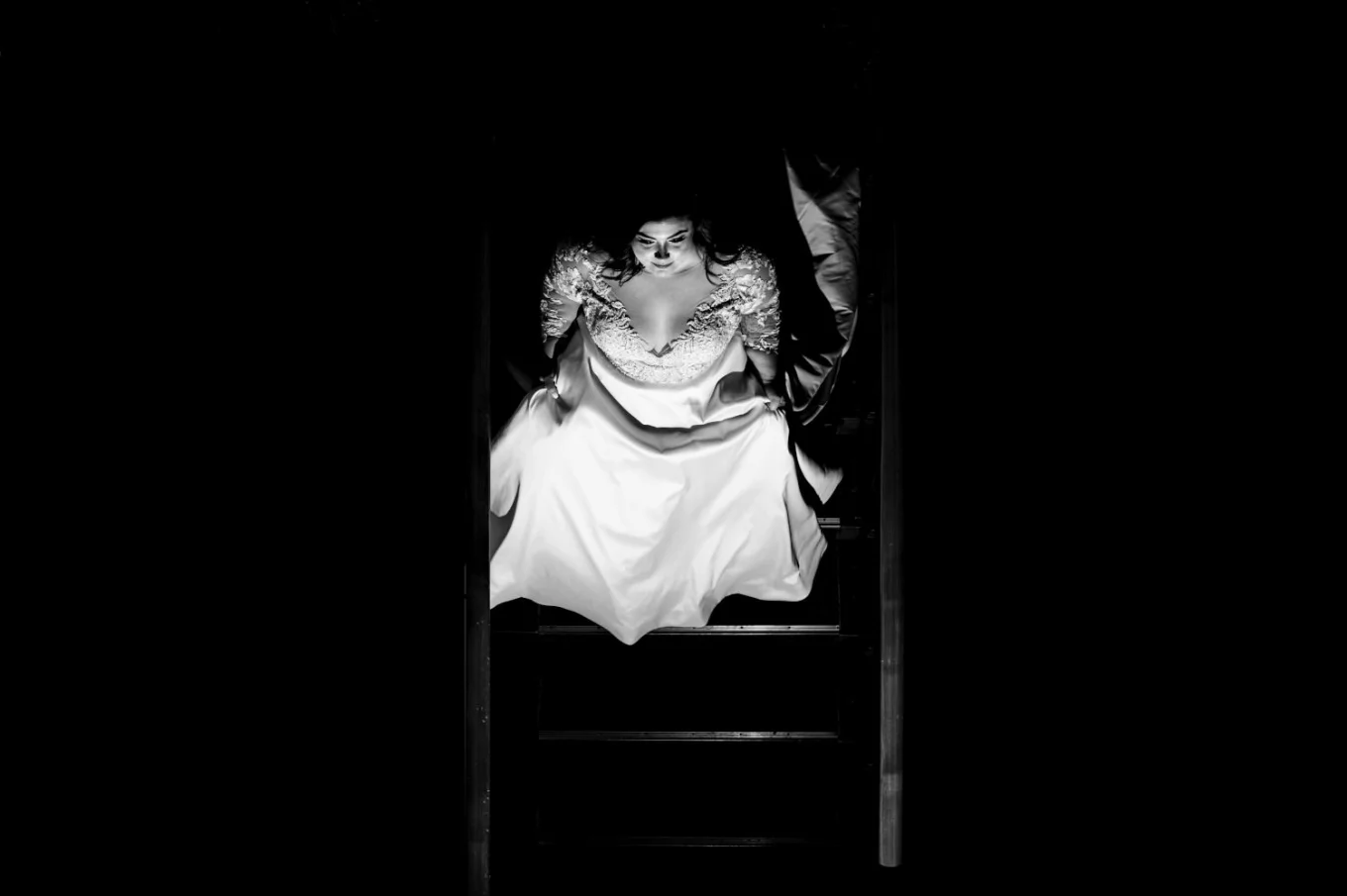 Black and white photograph of the bride walking down the stairs.