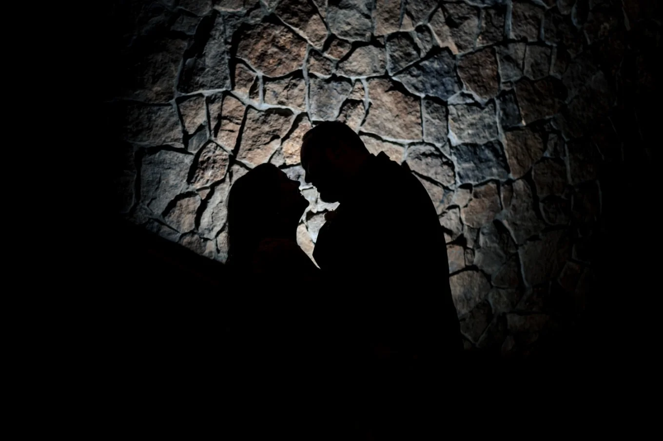 silhouetted photo of the bride and groom against stoned wall.