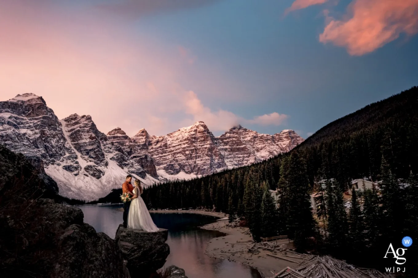 Married couple standing at the huge rock at Moraine Lake in Canada. Amazing moment captured by Calgary Wedding Photographer.