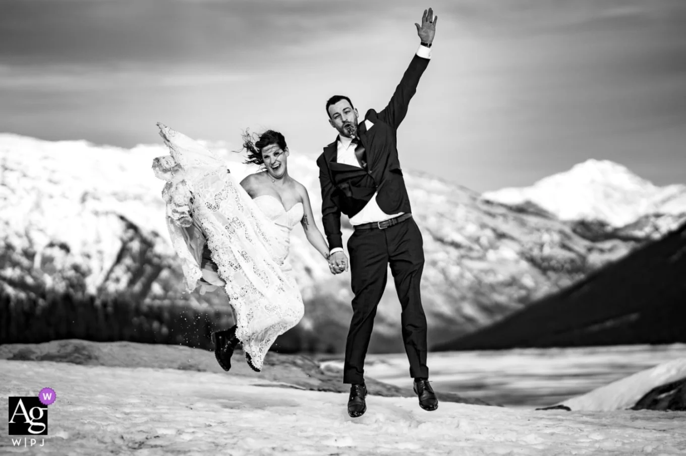 Happy bride and groom jumping after their elopement at Minnewanka Lake