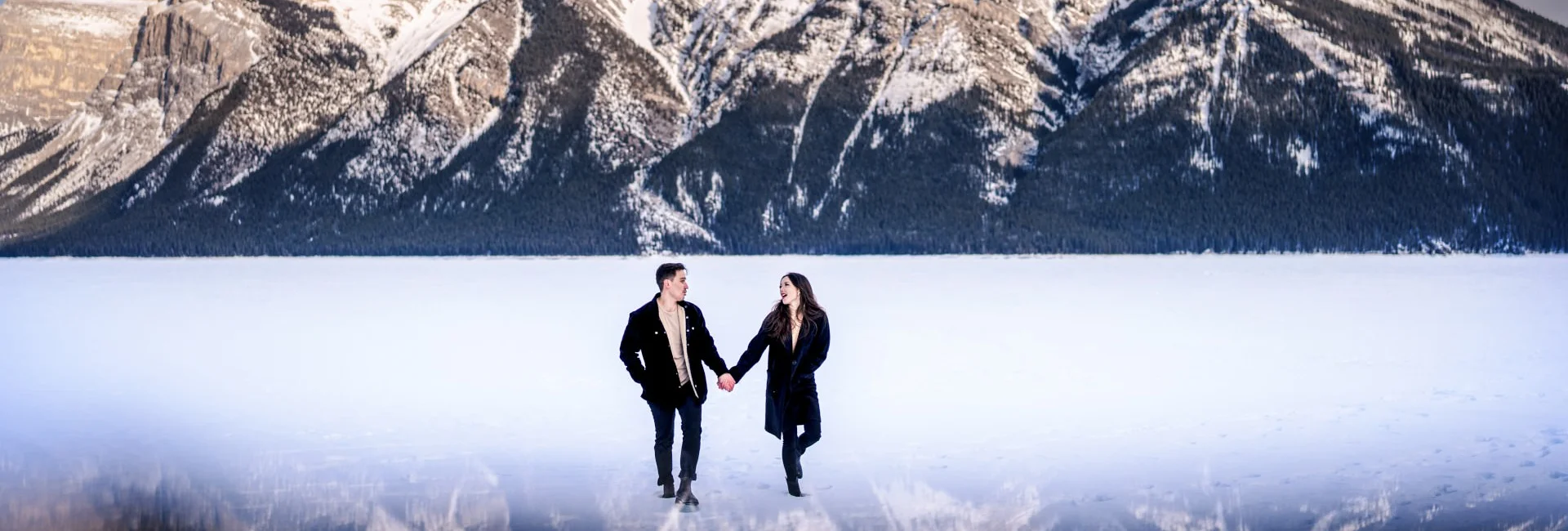 Photograph of the couple walking at the frozen Minnewanka Lake in Banff.