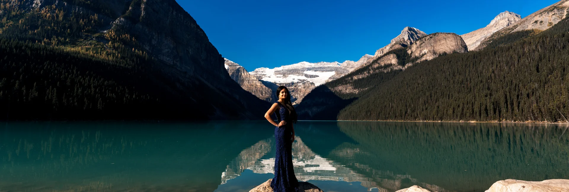 Beautiful in a purple long reass standing at the Lake Louise shore