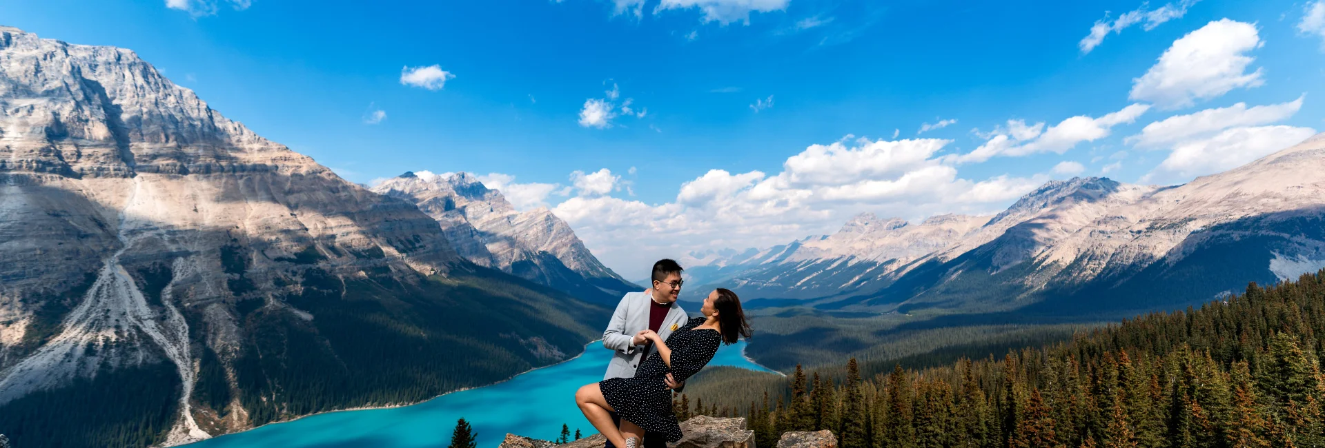 Engaged couple in love dance at Payto Lake against Rocky Mountains.
