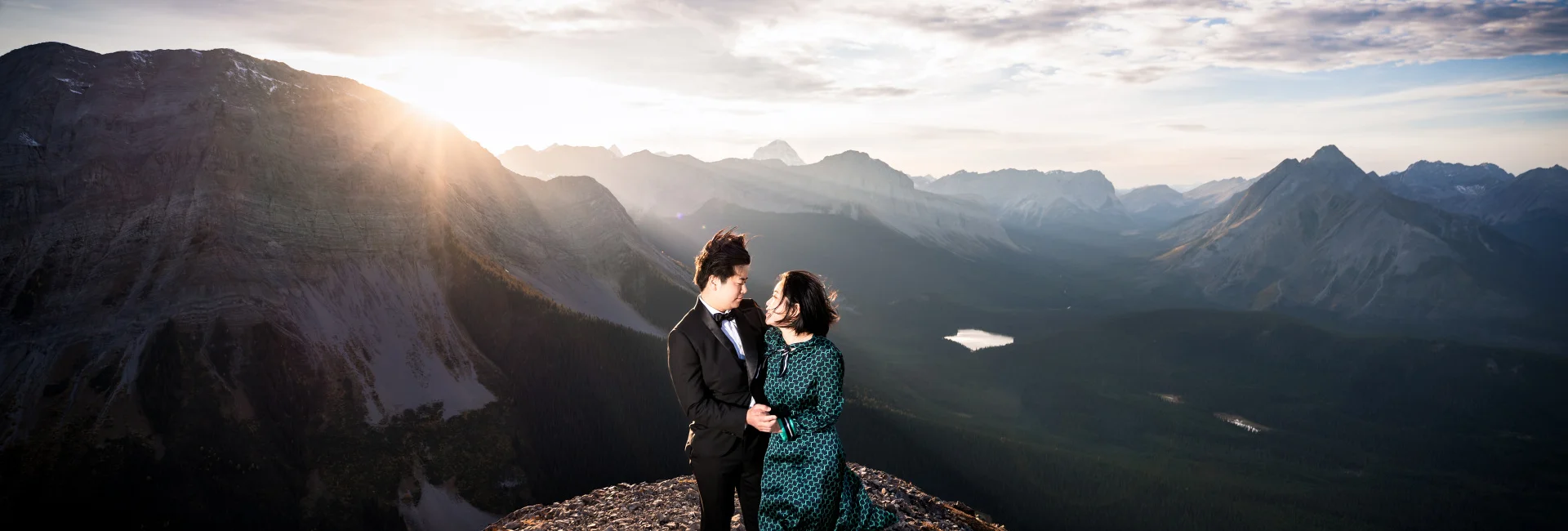 Engaged couple look at each other at the top of the mountain